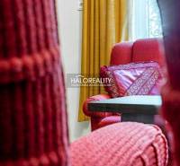 Red armchairs with patterned cushions and yellow curtains in the living area of a family house.
