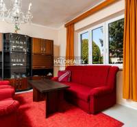 A living room in a family house with red furniture, a crystal chandelier, and a window.