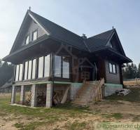 A wooden family house in Lom nad Rimavicou, with large glass sections and a sloped roof.