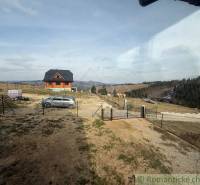 A view of a family house in Lom nad Rimavicou with a view of the hills and a car.