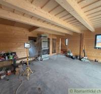 Wooden interior walls and a fireplace in a family house with unfinished flooring.