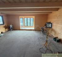 Interior of a family house with wooden paneling, incomplete flooring, and portable light.