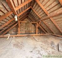 The attic of a family house in Čalovec with exposed wooden beams and a brick wall.