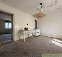 Abandoned room of a family house with simple furnishings and tiled walls.