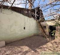 An older family house in Čalovec with a wooden ladder and blooming trees.