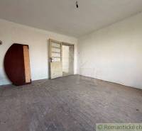 A room in a family house with an exposed floor featuring a wooden decor and white walls.