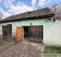 An old house with an open wooden gate, fenced in Čalovec.