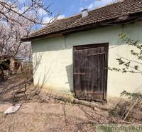 An older family house in Čalovec with wooden doors and blooming trees.