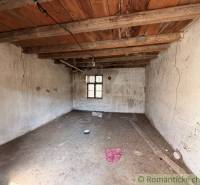 A shabby room in a family house with a wooden beam ceiling and a small window.