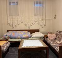 Living room in a family house with sofas, a coffee table, and lace curtains.