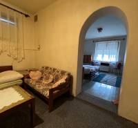 A room with simple furniture and an arched passage in a family house.