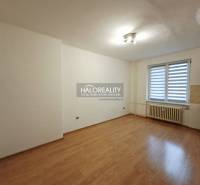 A room in a studio apartment with a wood-patterned floor and simple lighting.