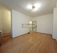 A studio apartment with a wooden floor and simple furnishings.