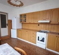 A kitchen in a family house with wooden decor, a stove, and a refrigerator.
