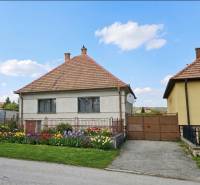 A family house in Trstín with a blooming garden and a blue sky.