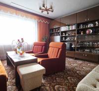 A living room in a family house with orange armchairs and dark furniture.