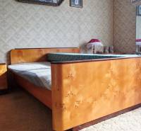 A bedroom in a family house with a wooden bed and paintings on the walls.