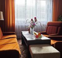 A living room in a family house with orange furniture and curtains.