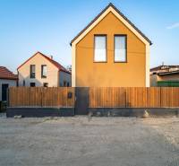 Front view of a fenced family house in Poprad with brown facade elements.