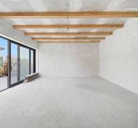 Spacious room in a family house with wooden beams and large glass doors.