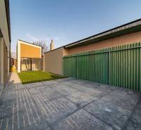 A family house in Poprad with a yard, a green fence, and concrete paving.