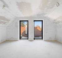 The interior of an attic in a family house with large windows and a view of the rooftops.