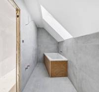 A bathroom in a family house with a bathtub and a skylight, white wall, gray tiles.