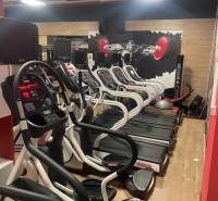 A gym with treadmills and a wooden decor floor in commercial premises.