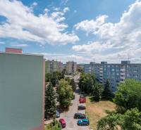 Apartment buildings in the Košice - Západ district, Pražská Street, surrounded by greenery and parked cars.
