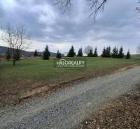 A residential building plot in Prešov with grass, trees, and a gravel road.