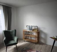 A room in a two-room apartment with an armchair, a table, and a floor with a wooden decor.