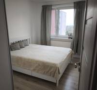 Svetlá spálňa s veľkým oknom a posteľou v 2-izbovom byte.