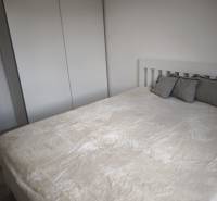 A bedroom in a 2-room apartment with a white wardrobe and a bed with pillows.