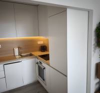 A kitchen in a 2-room apartment with light cabinets and a wooden decor floor.
