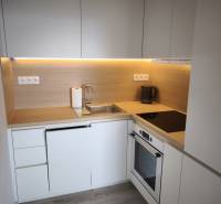 A kitchen in a 2-room apartment with white cabinets and a wood-patterned floor.