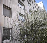 The exterior of an apartment building on Mozartova Street, Bratislava - Staré Mesto, surrounded by blooming trees.