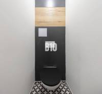 A toilet with a black seat and a geometric floor in a 3-room apartment.