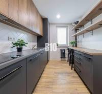 A kitchen in a 3-room apartment with a wooden decor floor and simple storage spaces.