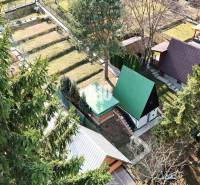 A cottage in Martin surrounded by trees, with several neighboring plots and a green roof.