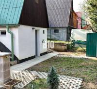 A garden with a cottage in Martin, a slide, stairs, green roofs, and a storage shed.
