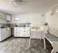 A bright cabin with a kitchenette, table, and bench, with a wooden decor floor.