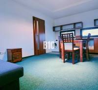 Living room with a sofa, dining table, and kitchenette in a three-room apartment.