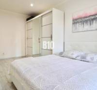 A bright bedroom with a double bed, a built-in wardrobe, and a wooden decor floor in a 2-room apartment.