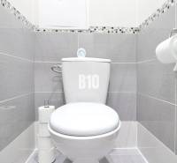 A bathroom in a 2-room apartment with a toilet, tiled with gray tiles.