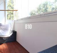 A glazed balcony in a 2-room apartment with a wooden decor floor and a hammock.