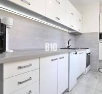 A kitchen in a 2-room apartment with white appliances and gray elements.