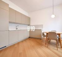 A kitchen in a family house with a wooden decor floor and a dining table with chairs.