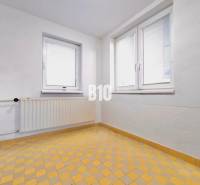 White wall, windows, radiator, and yellow tiled floor in a family house.