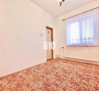 A room in a family house with a carpet, a radiator, and a curtain on the window.