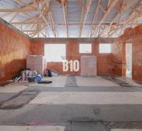 Construction of a family house with an unfinished wall and a wooden ceiling.